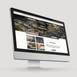 A computer monitor displays a real estate website for a development called The Foundry, featuring images of buildings and property details.