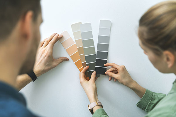 young couple choosing paint color from samples for new home inte