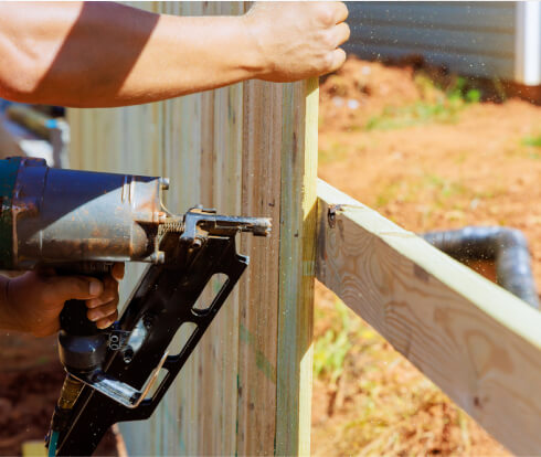 img - using-air-nail-gun-man-constructs-portions-wooden-fence