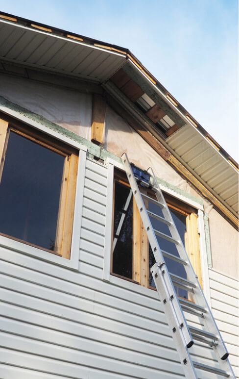 An extension ladder leaning against the side of a house under repair.