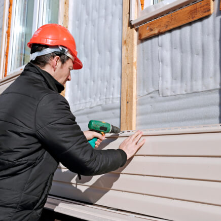 worker-installs-panels-beige-siding-on-the-facade
